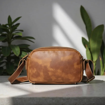 Brown leather crossbody bag viewed from the side with zipper closure and straps