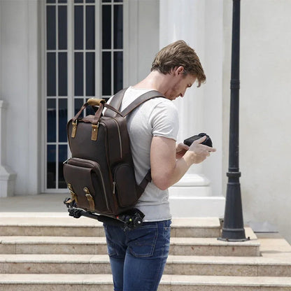 Brown leather camera backpack worn on back with side pockets and shoulder straps