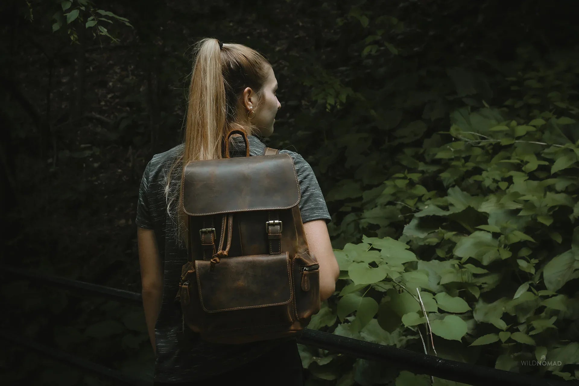 Brown vintage leather backpack worn on back with top flap and side compartments.