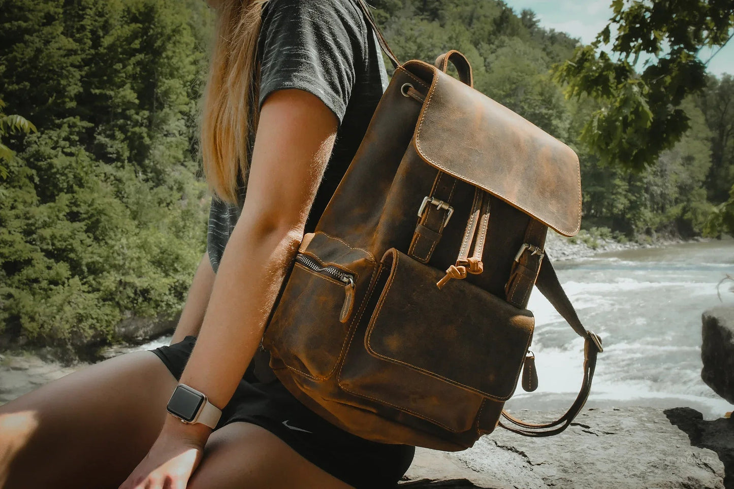 Brown vintage leather backpack worn on shoulder with flap and front pocket.