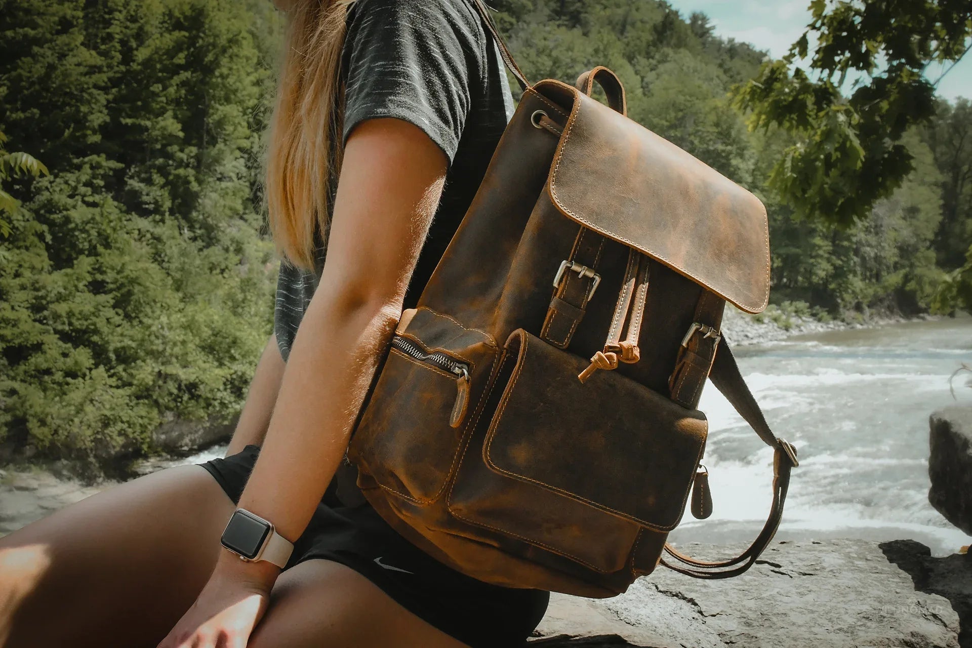 Brown vintage leather backpack worn on shoulder with flap and front pocket.