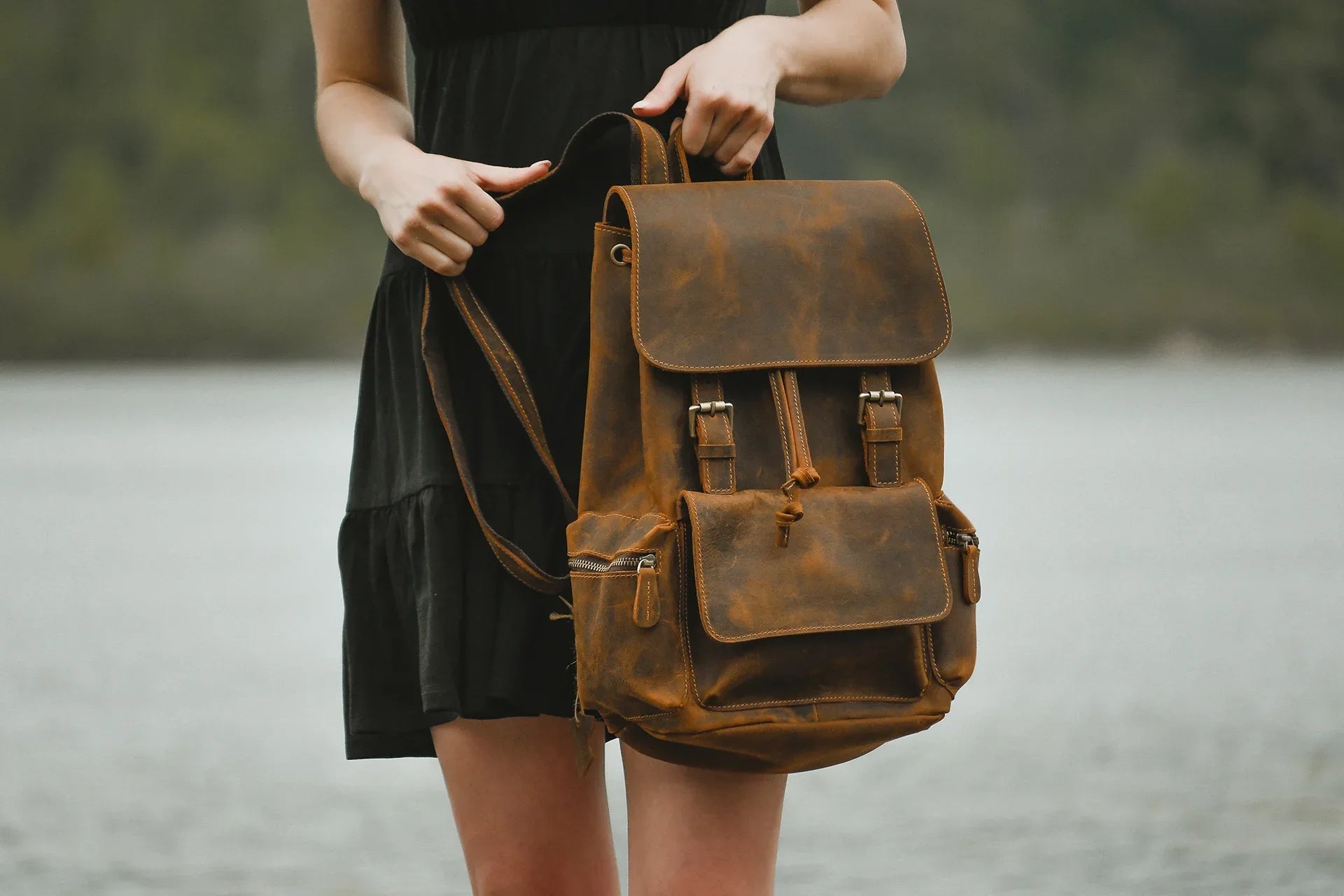 Brown vintage leather backpack with front flap and organizer pocket, carried by handle.