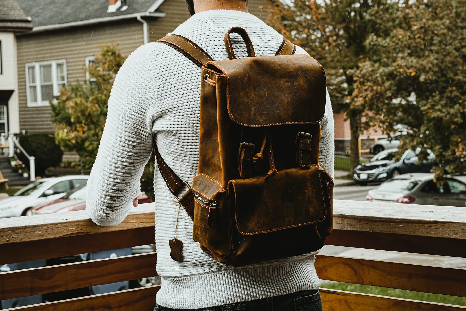 Brown vintage leather backpack worn with two shoulder straps and front flap pocket.