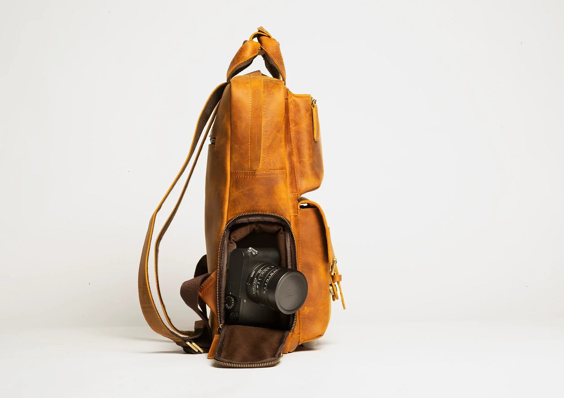 Brown leather camera backpack, side view with front opening and camera compartment