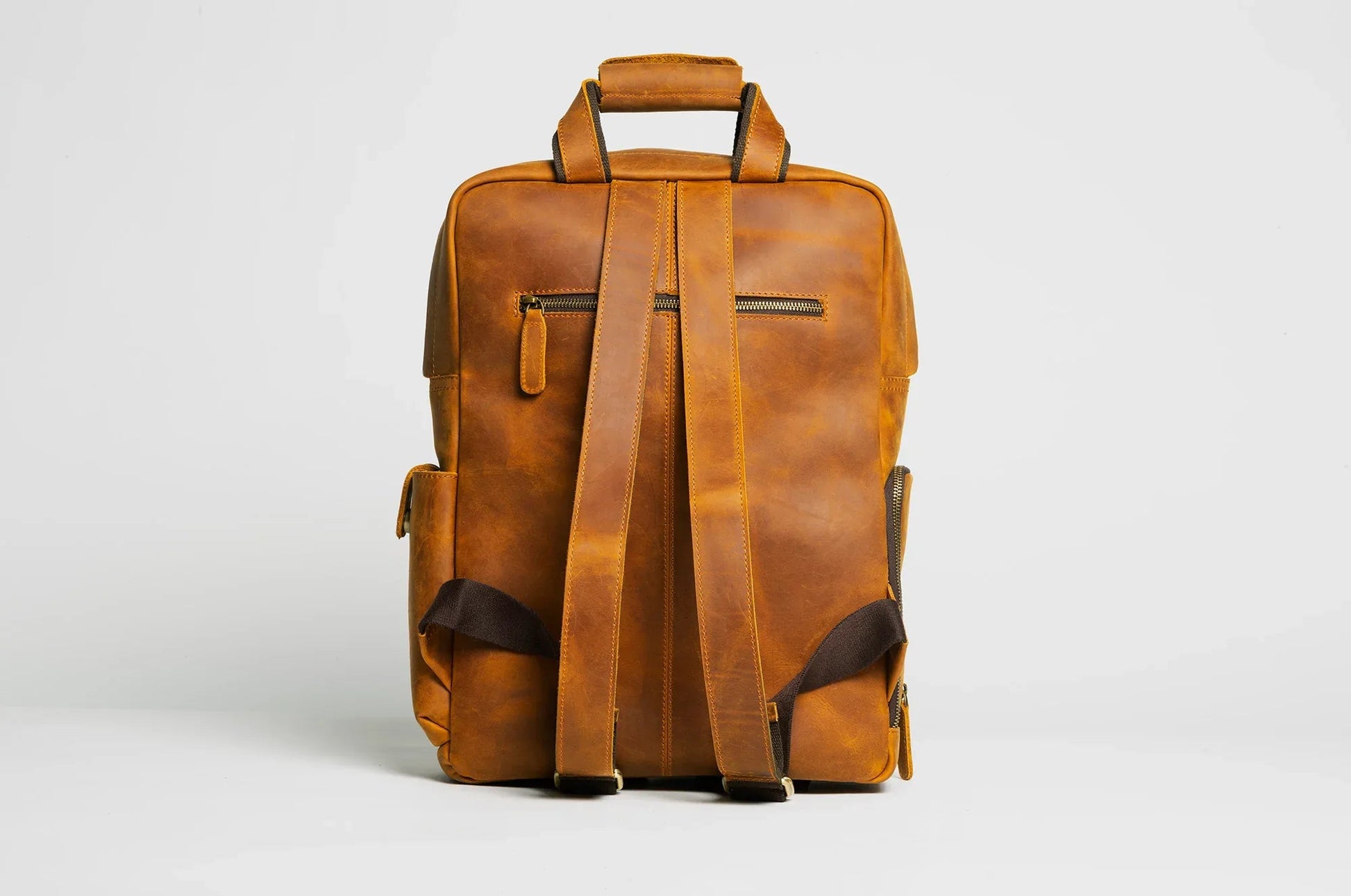 Brown leather camera backpack with back shoulder straps and top handle