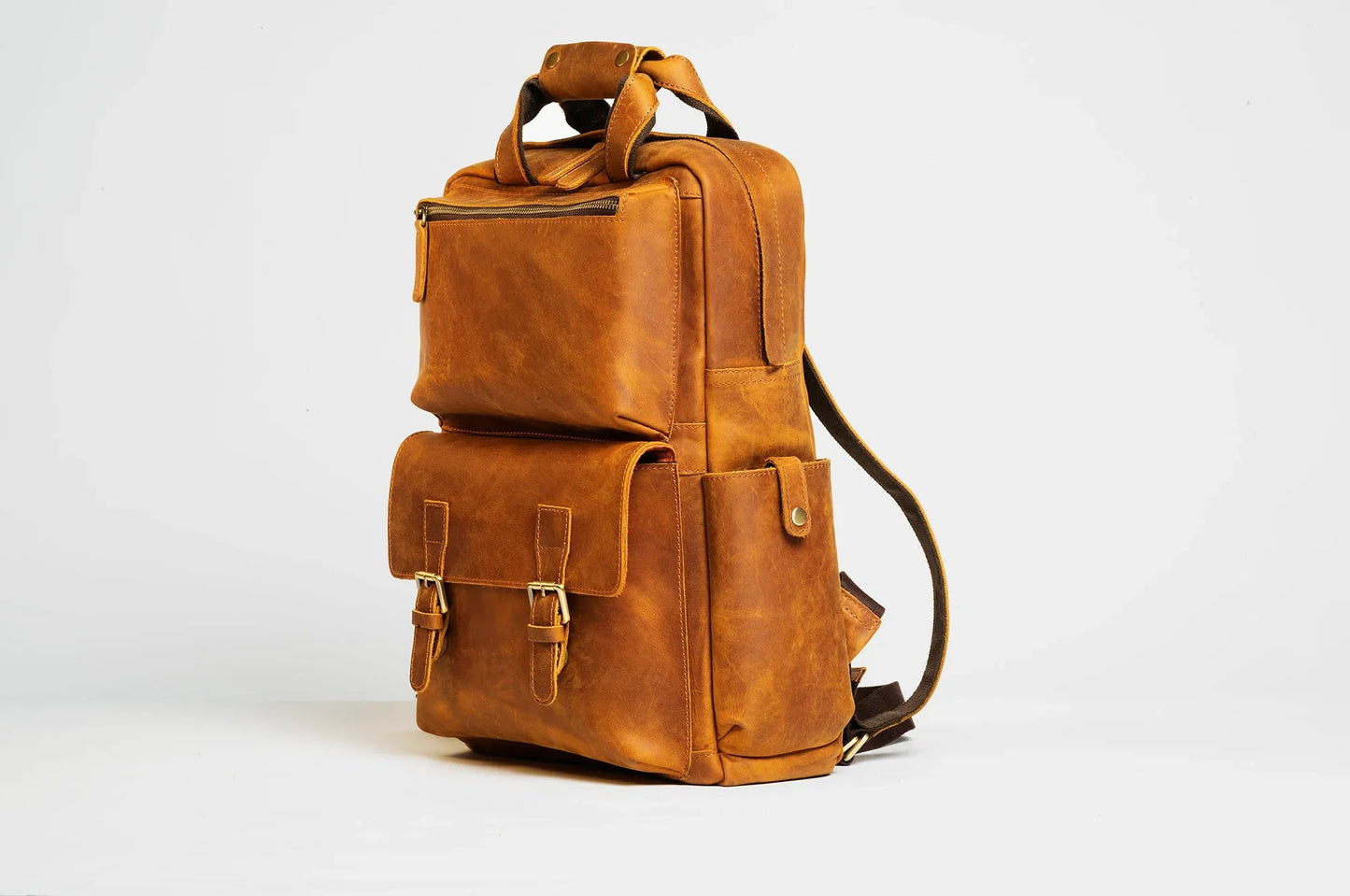 Brown leather camera backpack with two front pockets and side shoulder strap