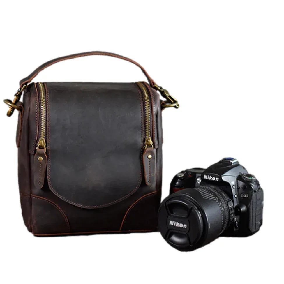 Small brown leather camera bag with top handle and front flap closure, brass hardware.