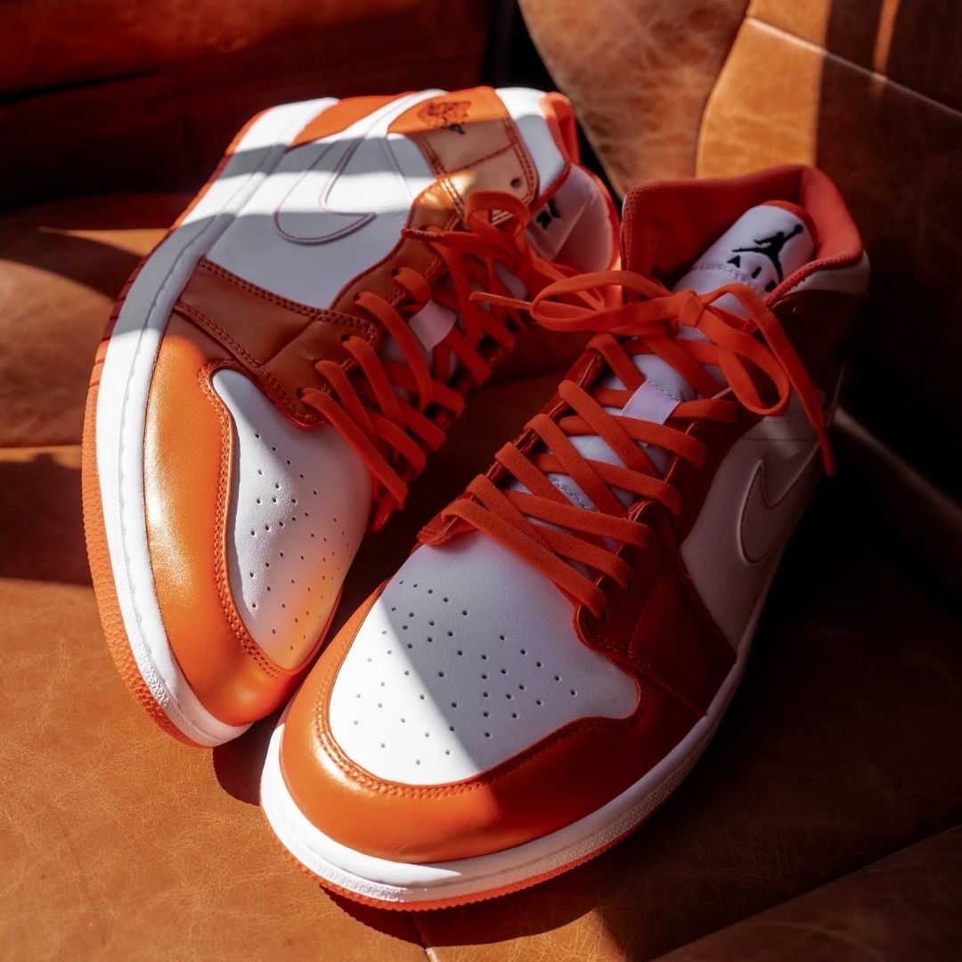 Orange and white sneakers with red laces on a wooden surface