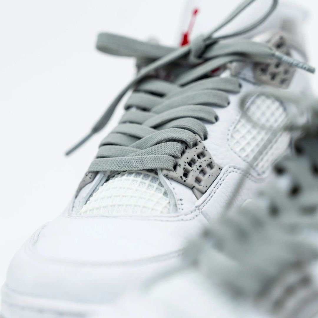 Close-up of a white sneaker with gray laces on a blurred background