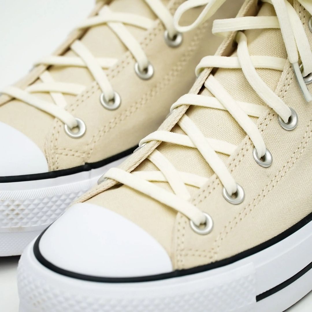 Close-up of beige high-top sneakers with white laces and soles.