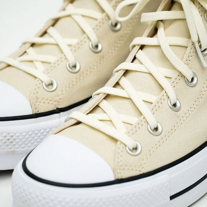 Close-up of beige high-top sneakers with white laces and soles.
