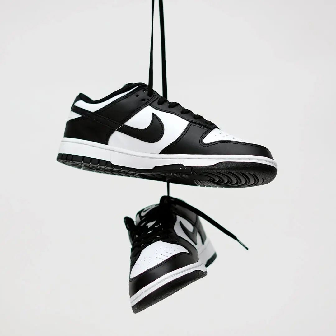 Black and white sneakers hanging against a light gray background