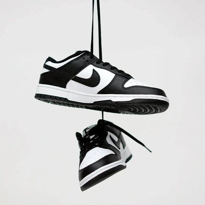 Black and white sneakers hanging against a light gray background