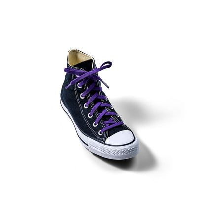 Black high-top sneaker with purple laces on a white background