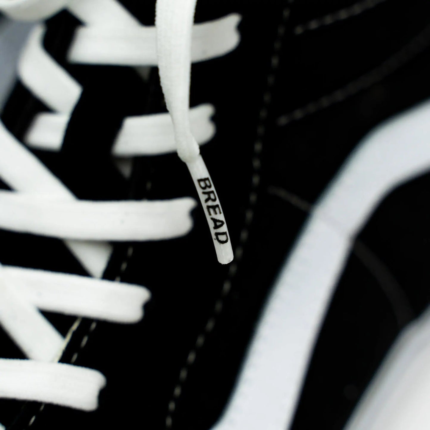 Close-up of a sneaker with white laces and a visible brand tag on a black background