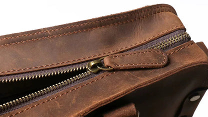 Brown leather zip opening with brass pull and contrast stitching along the edge