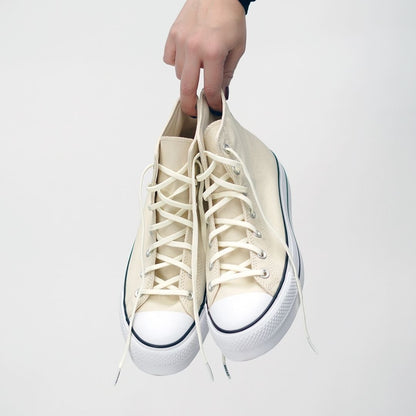 White high-top sneakers being held against a white background