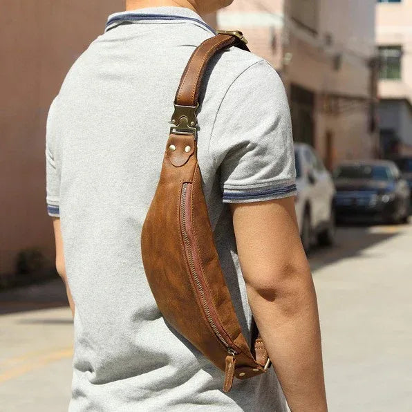 Brown leather fanny pack worn crossbody on a light gray shirt