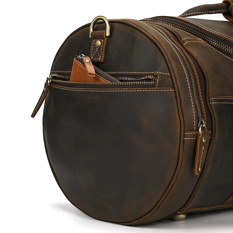 Close-up of round leather duffle bag front with zip track and leather strap tag