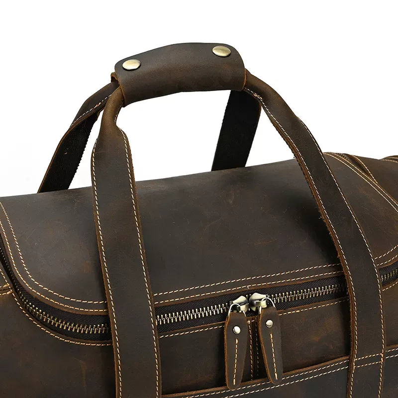 Brown leather duffle bag with metal-studded top handle and front double-zip detail.