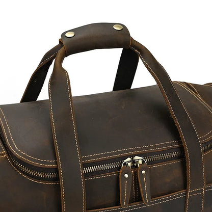 Brown leather duffle bag with metal-studded top handle and front double-zip detail.