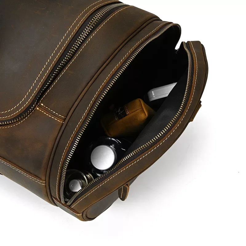 Brown leather duffle bag with open side showing inner pouches and small items.