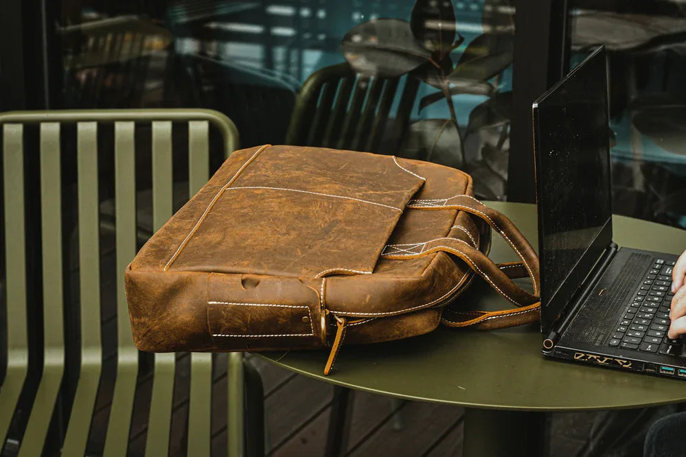 Vintage leather messenger bag with flap open and top handle, dark brown leather finish