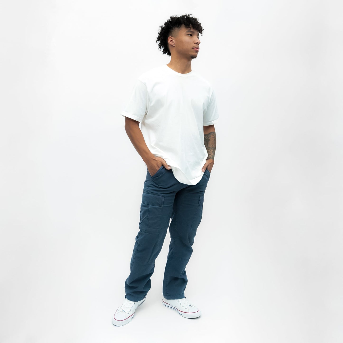 Man wearing a white t-shirt and blue jeans standing against a white background