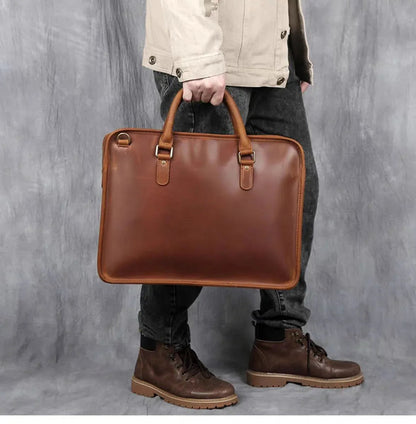 Vintage leather briefcase carried by person, brown with top handles and front buckle