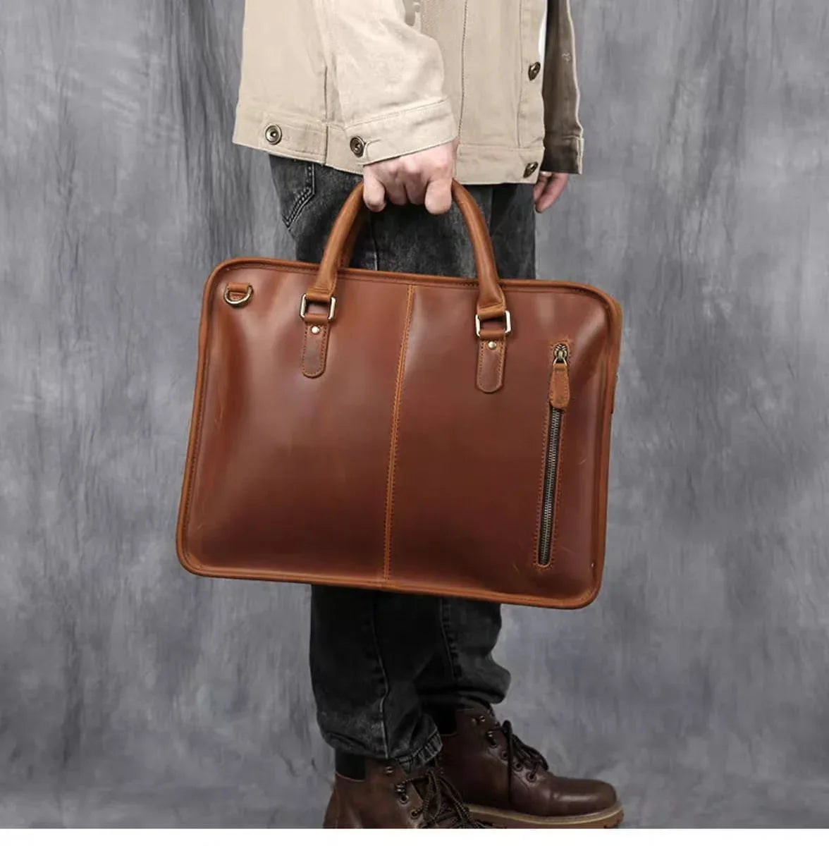 Vintage leather briefcase held by person, brown leather with top handles and zip detail