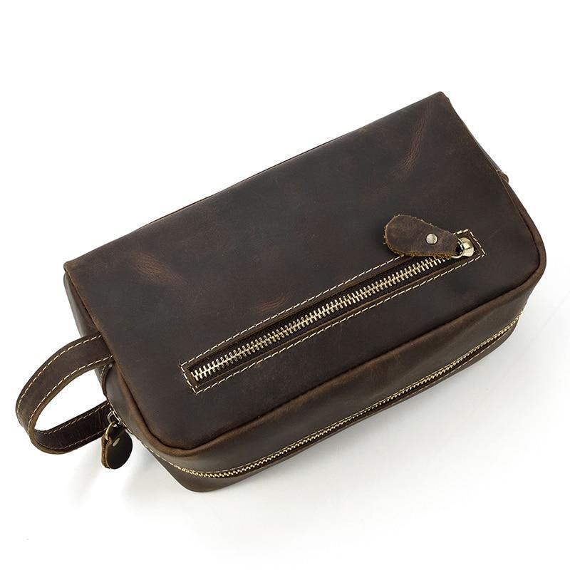 Dark leather toiletry bag with front zip pocket and crossbody-style wrist strap