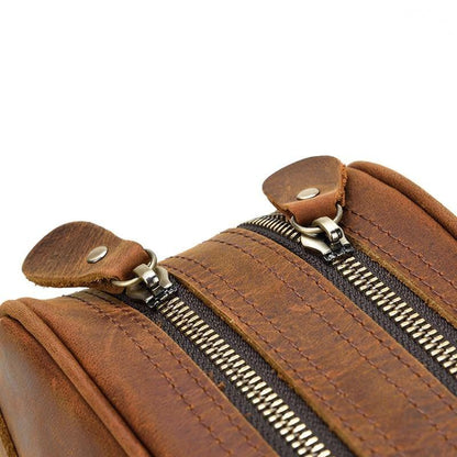 Close-up of leather toiletry bag zipper pulls and stitched tabs