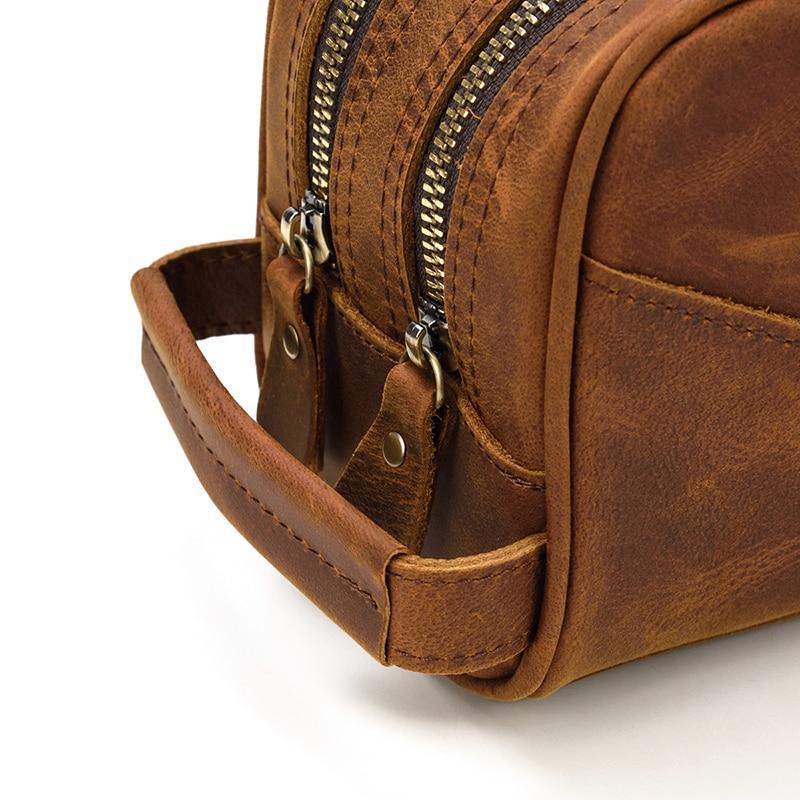Close-up of brown leather toiletry bag side strap and zipper edge