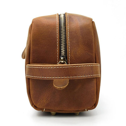 Brown leather toiletry bag rear view with vertical top zipper seam and base studs