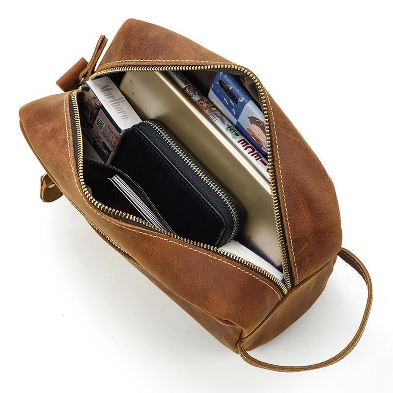 Open brown leather toiletry bag showing zip interior compartments and cards