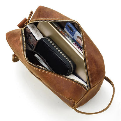 Open brown leather toiletry bag showing zip interior compartments and cards