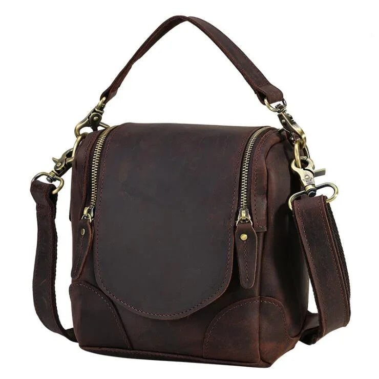 Brown leather camera bag with front flap, side panels, and adjustable shoulder strap