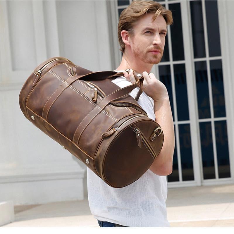 Brown leather weekender duffel bag with long shoulder strap and multiple front zip compartments.