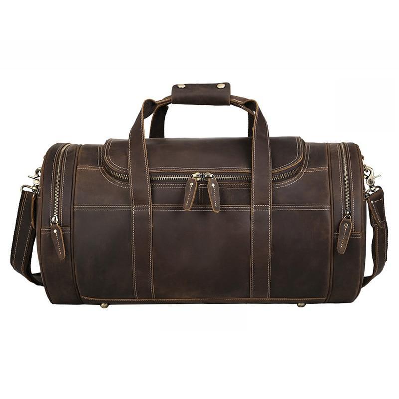 Brown leather round duffle bag with top handle, side zippers, and brass rivet accents.