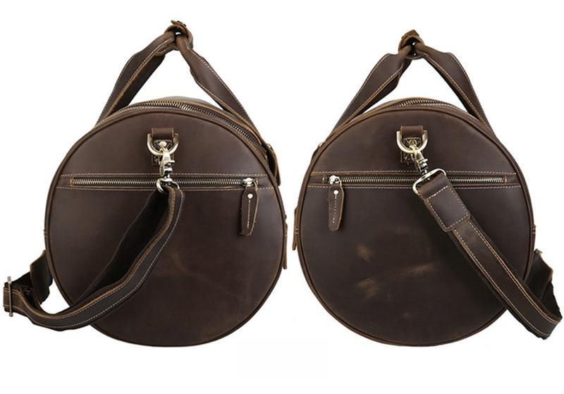 Pair of round brown leather duffel bags with zip front, crossbody strap, and metal hardware.