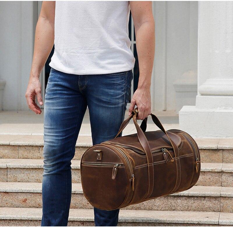 Brown leather round duffle bag on shoulder strap with front zip pockets and rivet details.