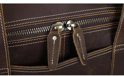 Brown leather round duffle bag with front zip pocket and brass-toned metal pulls.