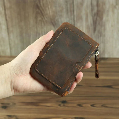 Brown leather coin purse held in hand, zipper on the side and stitched corners.