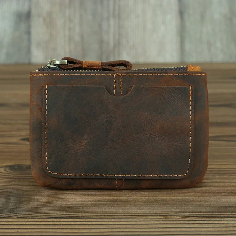 Brown leather coin purse with zipper, front pocket detail and stitched borders.