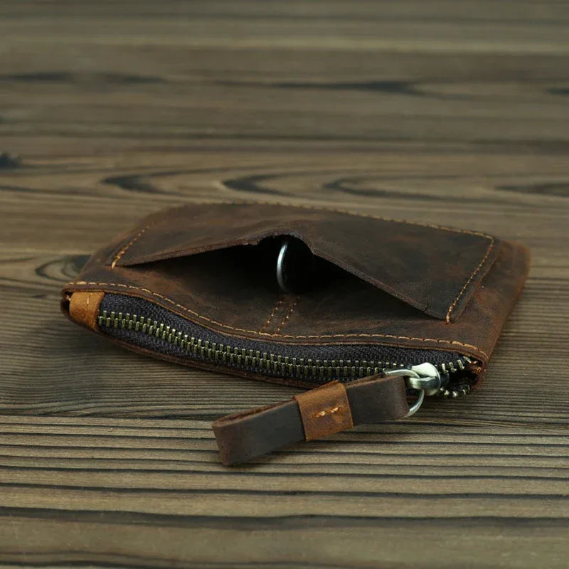 Brown leather coin purse with zipper open, card compartment and metal pull visible.