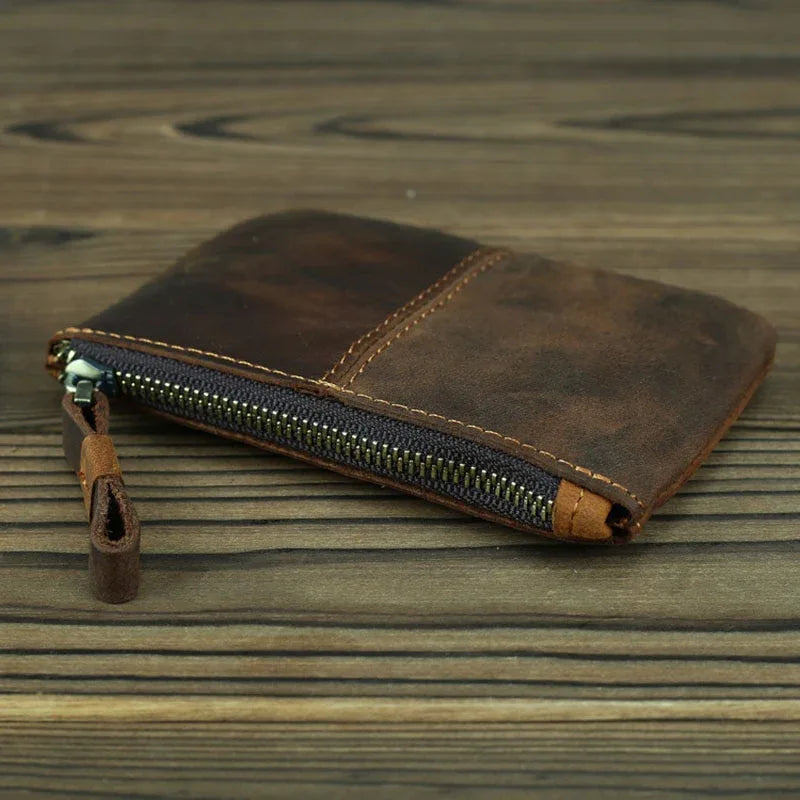 Brown leather coin purse with open zipper showing interior, leather tab ends.