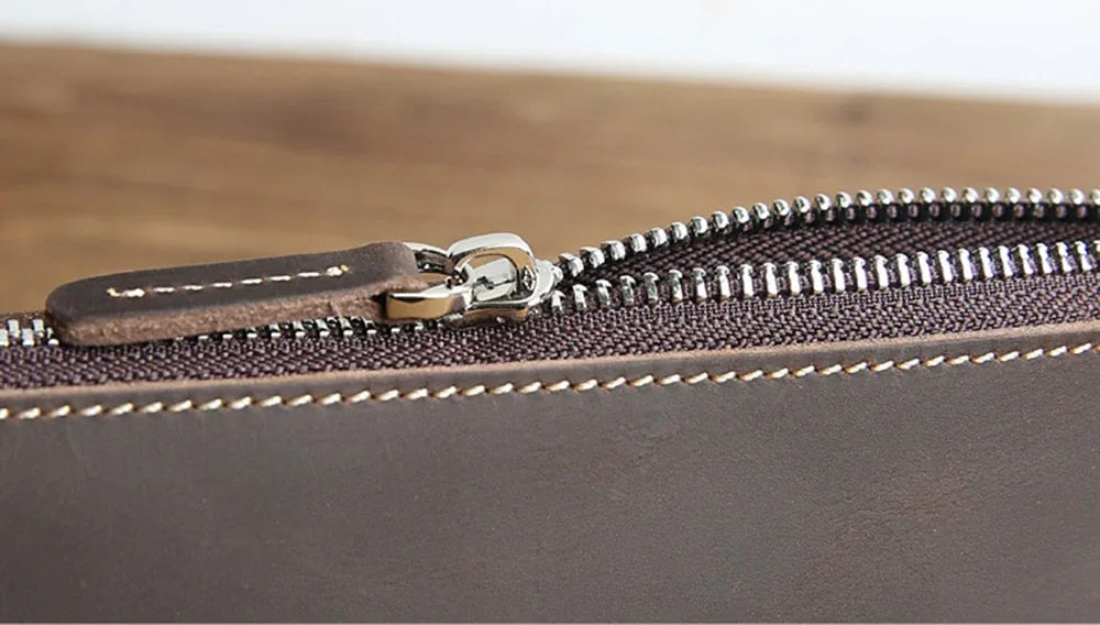 Close-up of brown leather pencil case zipper pull with metal hardware and stitching