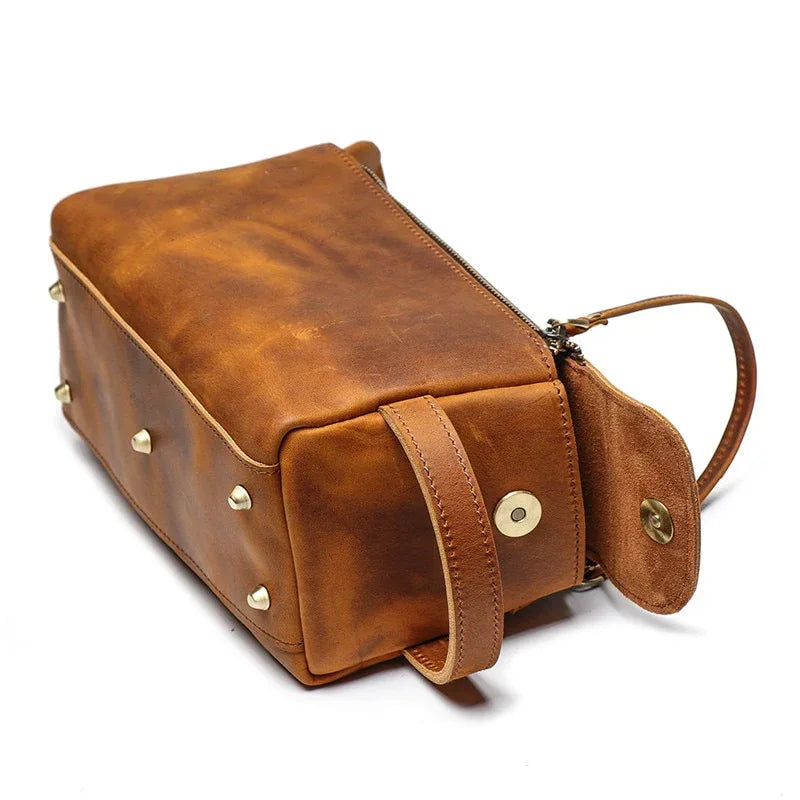 Leather toiletry bag with flap pocket and brass studs, side carry strap