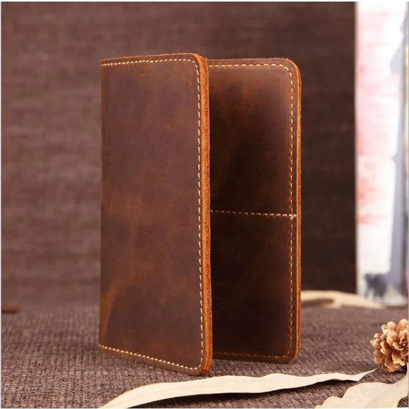 Brown leather passport cover, standing closed with contrast edge stitching.