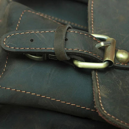 Leather flap strap detail with brass turn-lock and contrast stitching